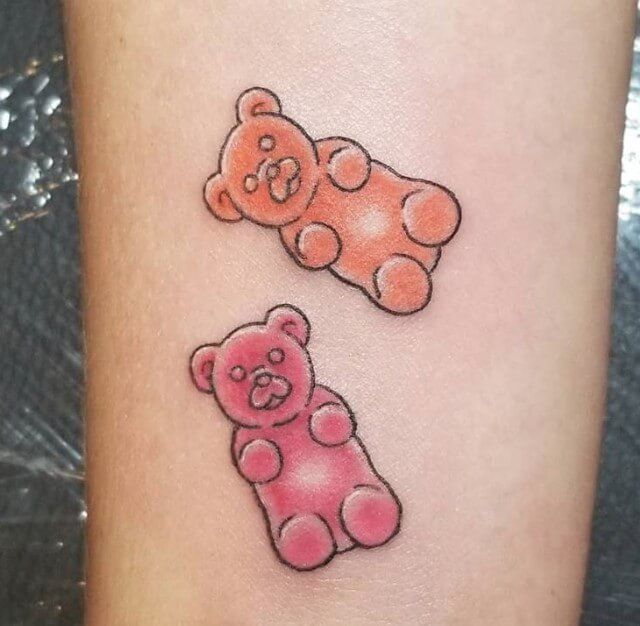 two small teddy bears on the side of a woman's leg, one pink and one orange