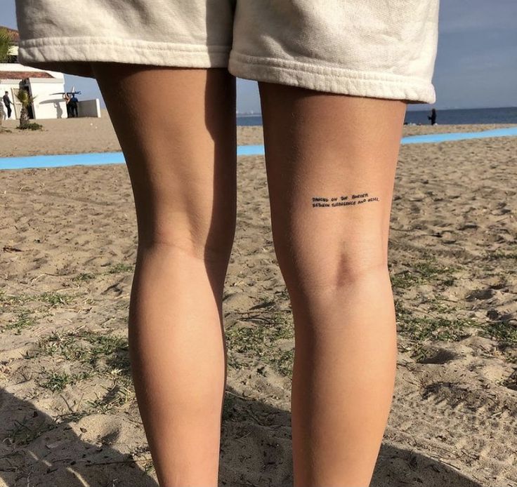 a person standing on top of a sandy beach next to the ocean with their legs crossed