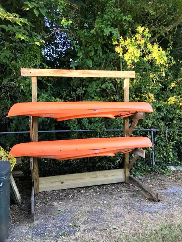 three orange kayaks sitting on top of a wooden stand