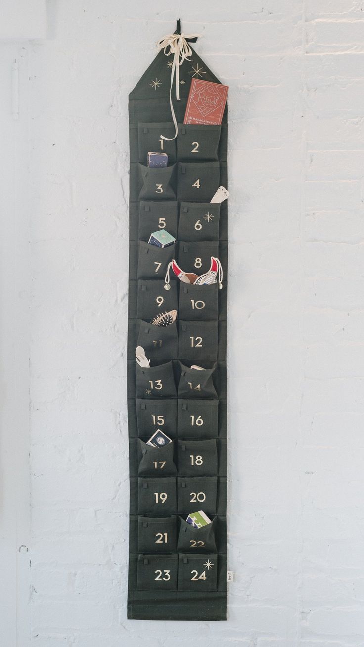 a black wall hanging calendar on a white brick wall with numbers and magnets attached to it