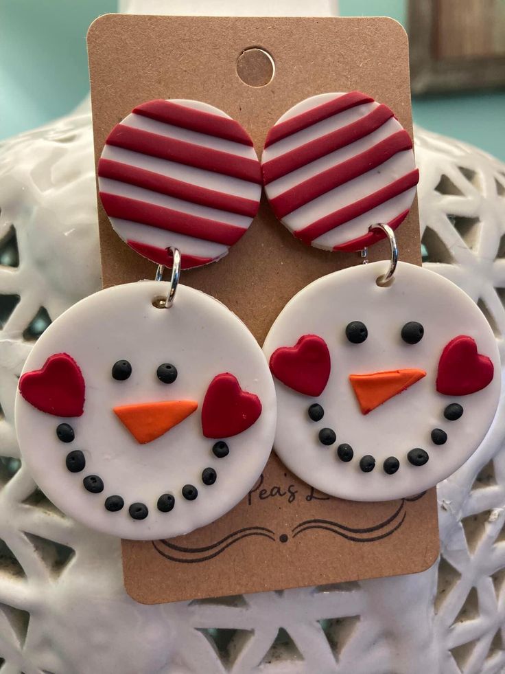 two snowmen with red and white hearts on their ears are sitting next to each other