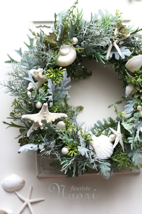 a christmas wreath with seashells, greenery and starfish hanging on the wall