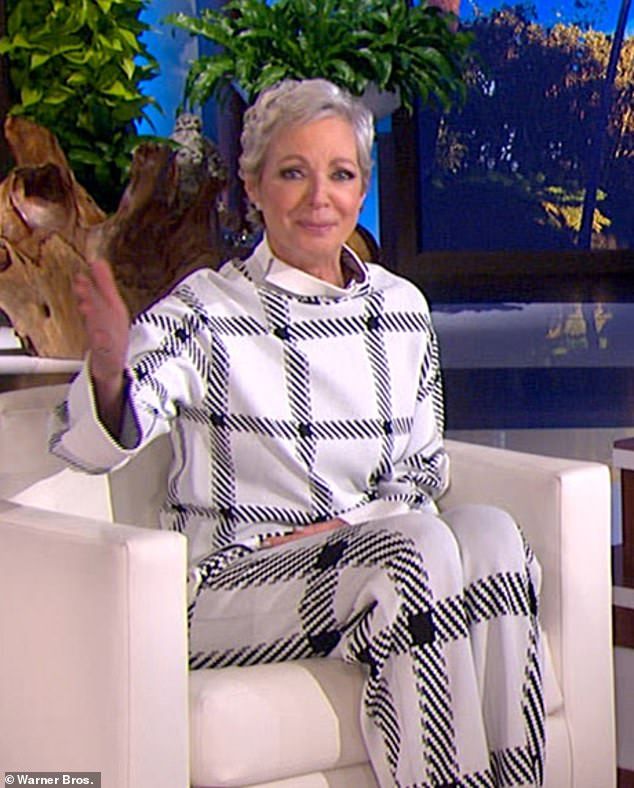 an older woman sitting in a chair with her hand up to the side and wearing black and white checkered pants