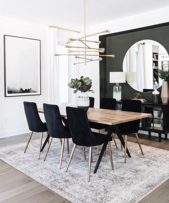 a dining room table with black chairs and a mirror on the wall in front of it