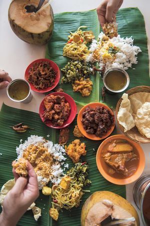 people sitting at a table with plates of food on top of it and bowls of sauces in front of them