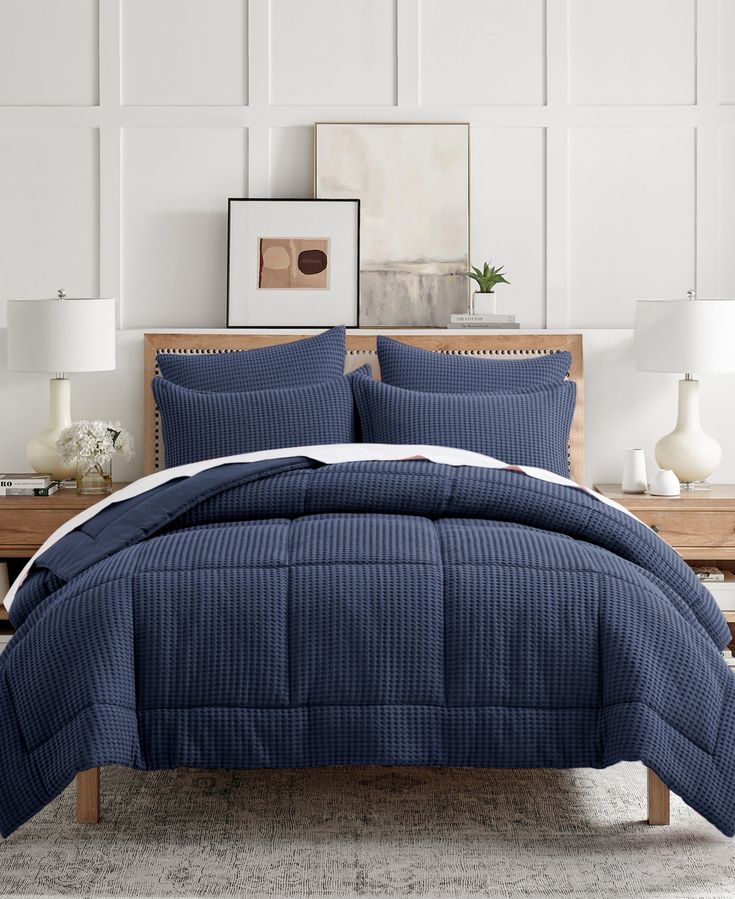 a bed with blue comforter and pillows in a room next to a wooden table