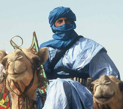 a man riding on the back of a camel wearing a blue cloth over his head