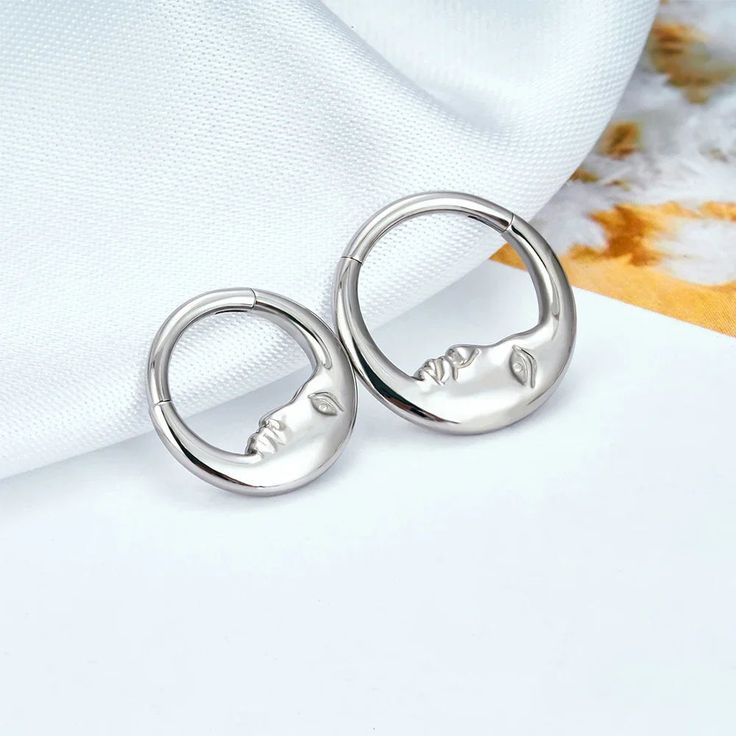 the silver hoop earrings are on top of a white cloth