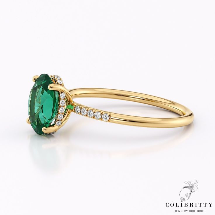 an oval shaped green stone with diamond accents on the side and sides, set in yellow gold