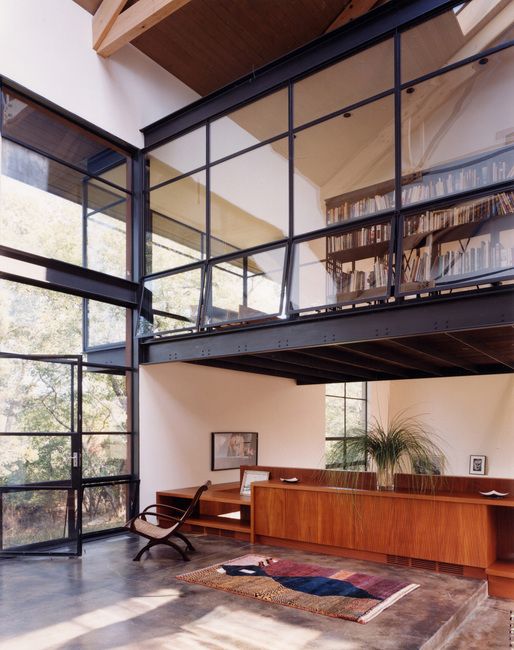 an open living room with lots of windows and furniture on the second floor, along with bookshelves