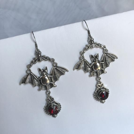 These large gothic vampire inspired earrings are made with antiqued silver plated bats, filigrees and stainless steel earring hooks,  accented with sparkling glass crystals in DARK RUBY RED. Earrings measure 3 1/2" tall and are 1 7/8" wide.Matching necklace is available in our shop. If you would like these in a different stone color, please send us a message. Silver Punk Jewelry For Costume, Silver Punk Costume Jewelry, Punk Style Silver Jewelry For Costumes, Gothic Silver Metal Earrings, Silver Gothic Metal Earrings, Silver Vampire Costume Jewelry, Silver Vampire Style Costume Jewelry, Gothic Silver Pierced Earrings, Vampire Style Metal Earrings For Halloween