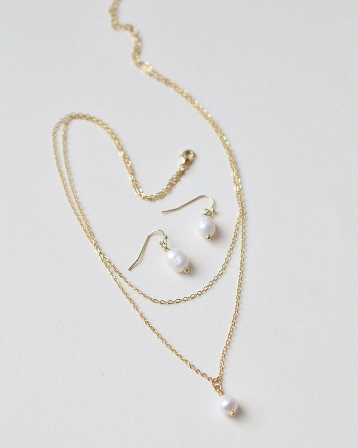 Elegantly modern, our Layered Chain Pearl Drop Jewelry Set is the perfect balance of minimalist style with timeless chic. Crafted with delicately layered chains and a single freshwater pearl drop, this set will become your everyday go-to. Crafted with a double chain & single freshwater pearl. The beauty & dimension of freshwater pearls come from the slight variations in shape & hue. Freshwater pear earrings measure .5 inches long. Longer chain measures 16.5 inches unclasped with the extender cha Pearl Bridesmaid Jewelry, Drop Earrings Simple, Gold Drop Necklace, Silver Drop Necklace, Bridesmaids Jewelry, Drop Jewelry, Pear Earrings, Bridesmaids Gift Sets, Freshwater Pearl Drop Earrings