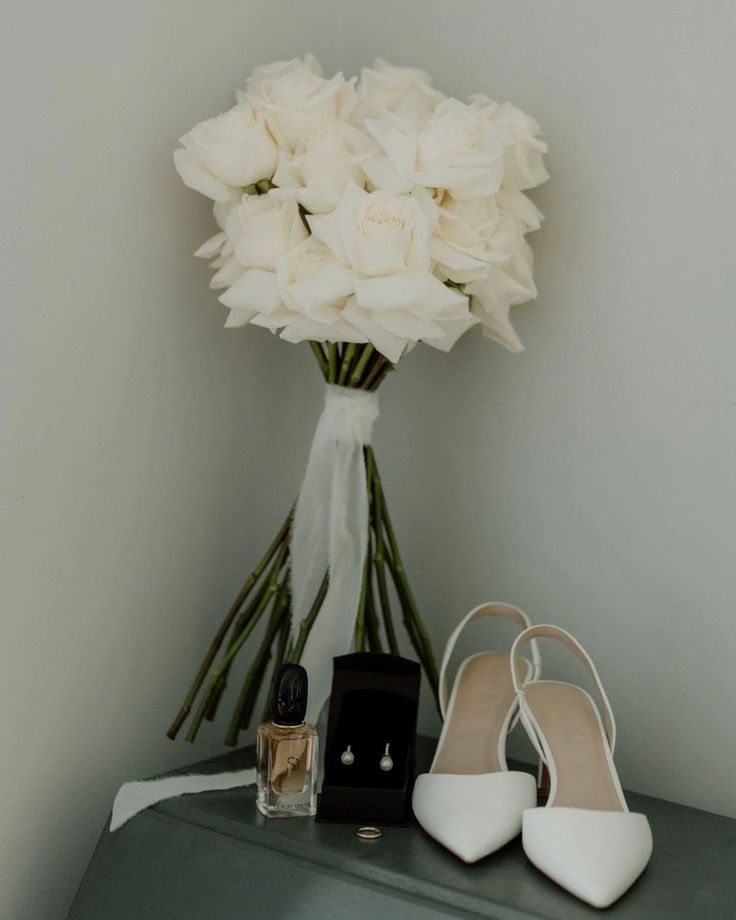 a bouquet of white flowers sitting on top of a table next to two pairs of shoes