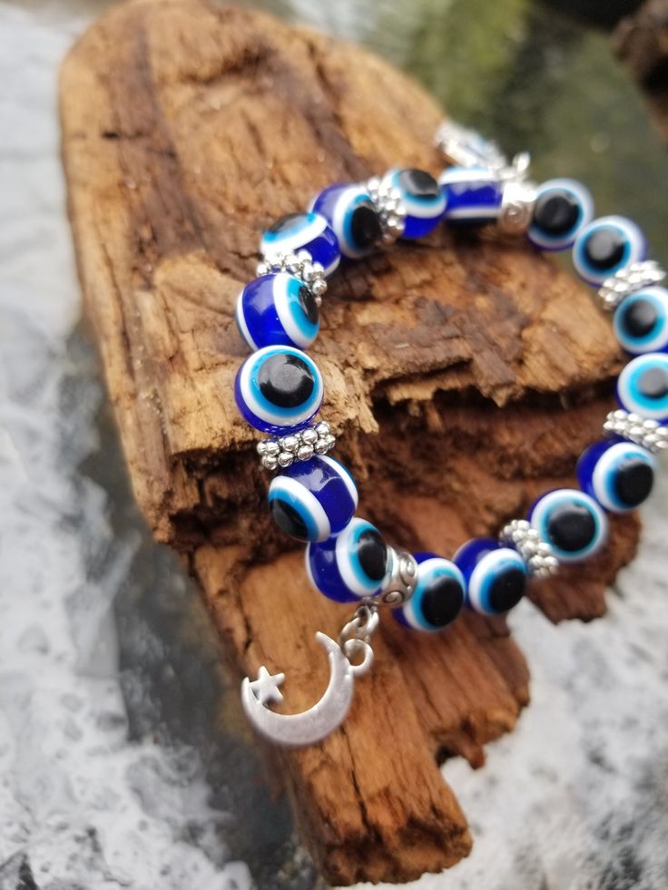 a bracelet with evil eye beads and a crescent charm on top of a piece of wood