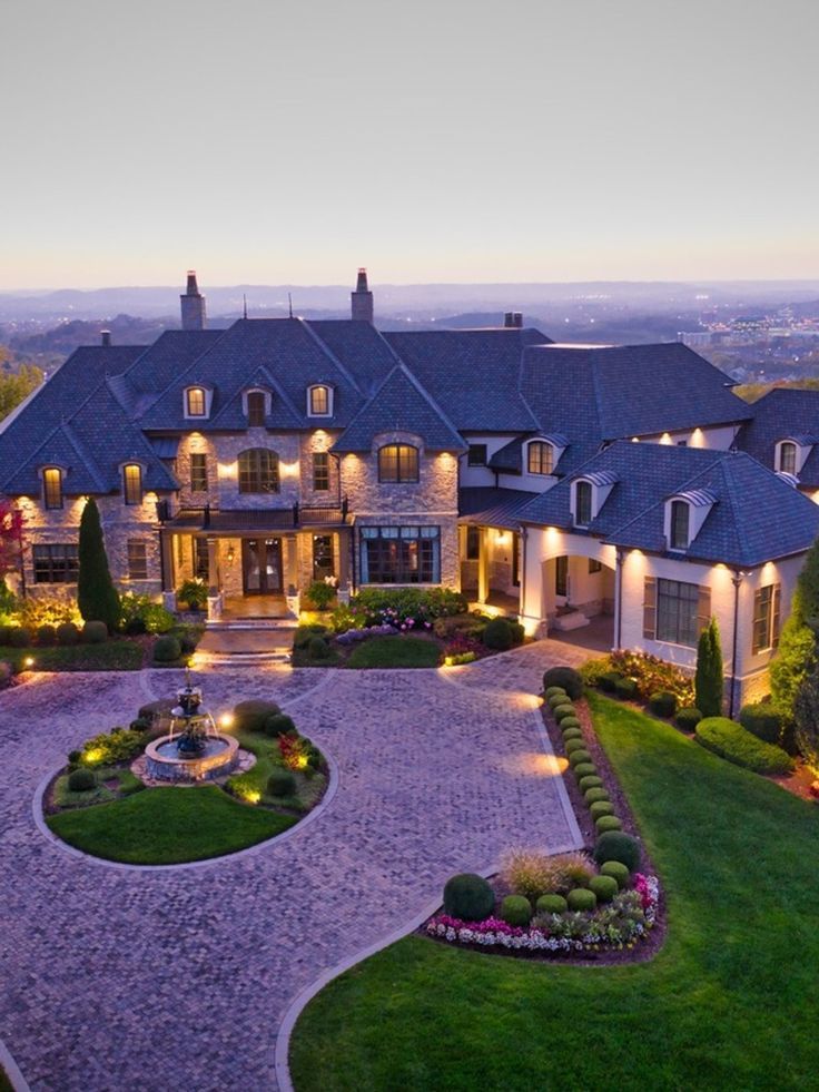 an aerial view of a large home with landscaping and lights in the front yard at dusk