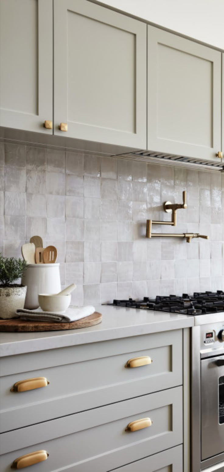 a kitchen with white cabinets and gold handles on the stove top, next to an oven