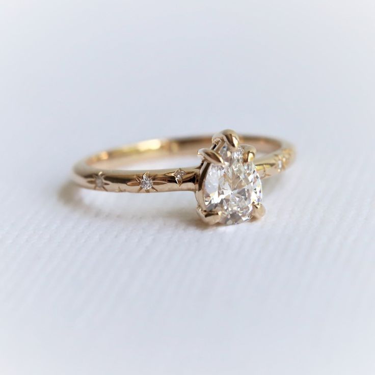 a close up of a diamond ring on a white surface with the center stone in yellow gold