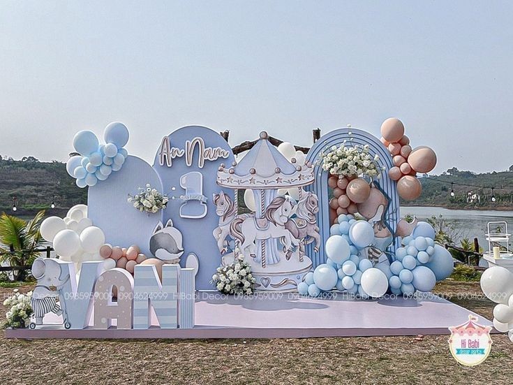 an outdoor stage set up for a baby's first birthday with balloons and decorations