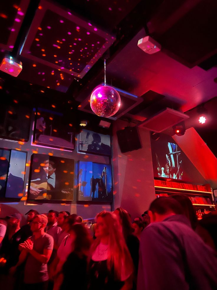 a group of people in a room with disco balls on the ceiling and lights hanging from the ceiling