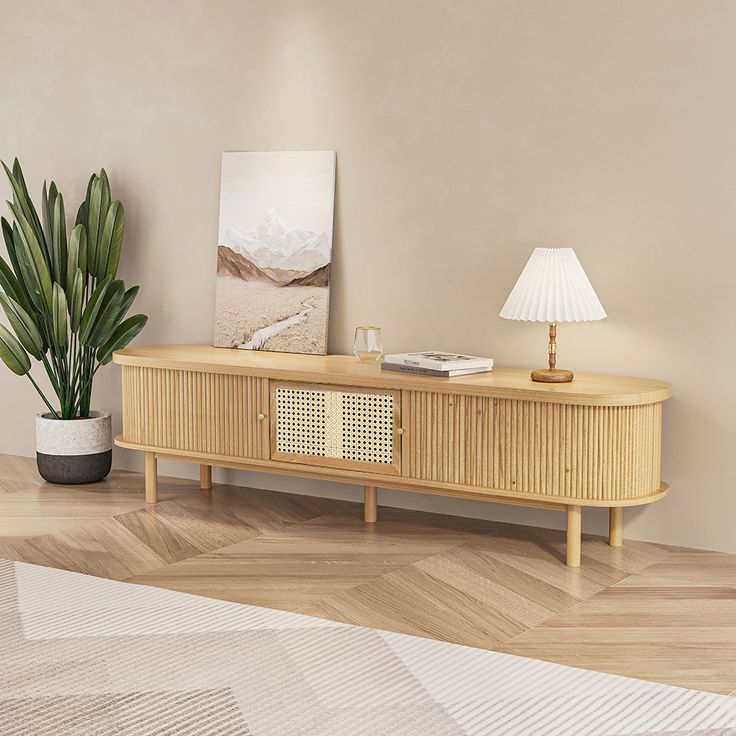 a living room with a plant on the sideboard and a lamp next to it