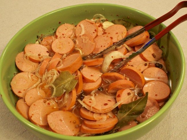 a green bowl filled with sliced carrots and onions