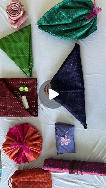 several different types of cloths laid out on top of a white bed with pink and green flowers