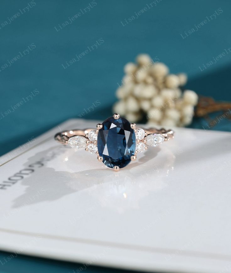 an oval blue sapphire and diamond ring sitting on top of a card