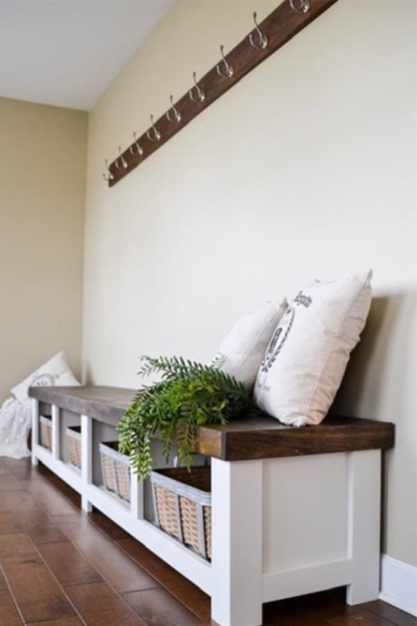 a white bench with some plants on top of it next to a wall mounted coat rack