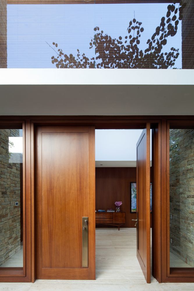 two wooden doors are open in front of a brick wall and glass windows on the outside