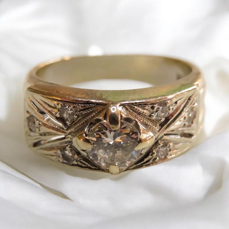 a gold ring with a diamond in the center on a white cloth background, close - up