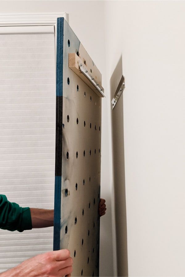 a man is working on a piece of metal that has holes and screws attached to it