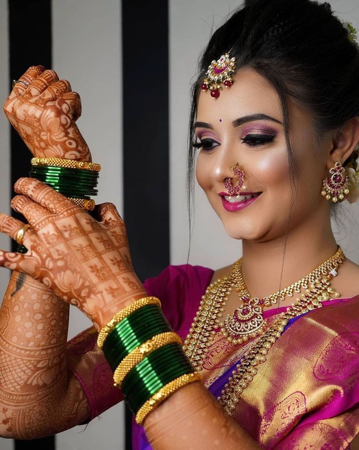 a woman with henna and jewelry on her hands holding something in front of her face