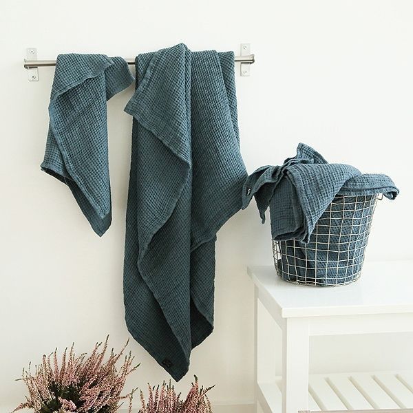 two towels are hanging on the wall next to a basket with flowers and a plant