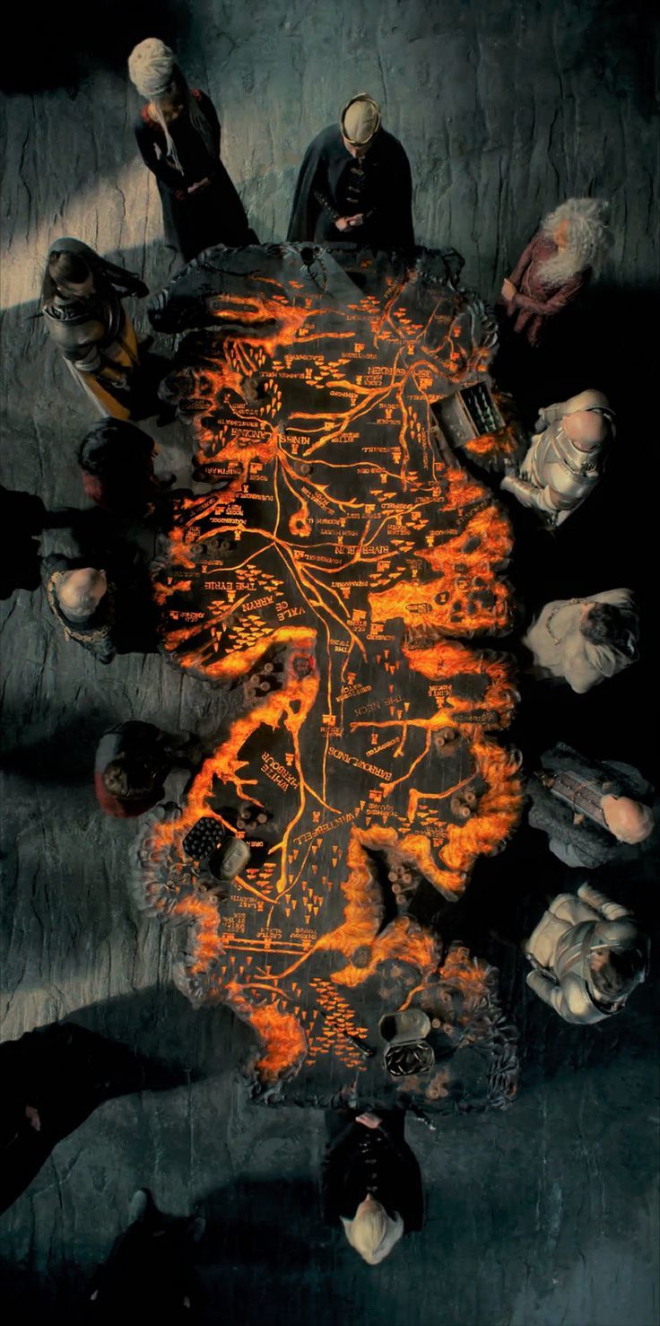 a group of people sitting around a table covered in orange and black fire with faces drawn on it