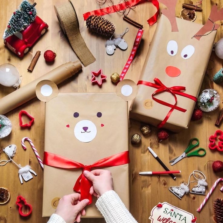 a person wrapping presents on a table with christmas decorations and other items around it,