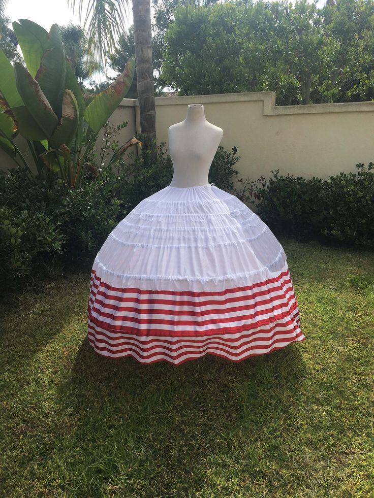 a mannequin is dressed in red and white striped fabric, while sitting on the grass