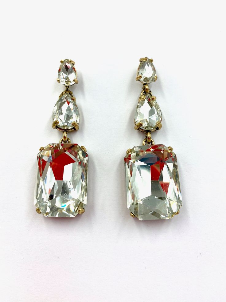 These Stunning Tammie Earrings are perfect for all occasions, weddings, bridal, engagements, parties, dinner dates, holidays, and cruises. These earrings are made up of two smaller gemstones, with a third gemstone hanging loosely to give them sophistication. Stud Style closure. With every pair of earrings sold, you receive a spare set of backs  Drop: Approximately 6cms Width: Approximately 2cms Classic Dangle Diamond Earrings For Evening, Classic Evening Dangle Diamond Earrings, Clip-on Drop Earrings For Bridal Evening, Elegant Diamond White Clip-on Jewelry, Formal Sparkling Crystal Earrings, Celebration Diamond Drop Earrings, Jeweled Drop Earrings For Celebrations, Formal Crystal Earrings With Sparkling Stones, Dazzling Crystal Earrings With Sparkling Stones For Formal Occasions