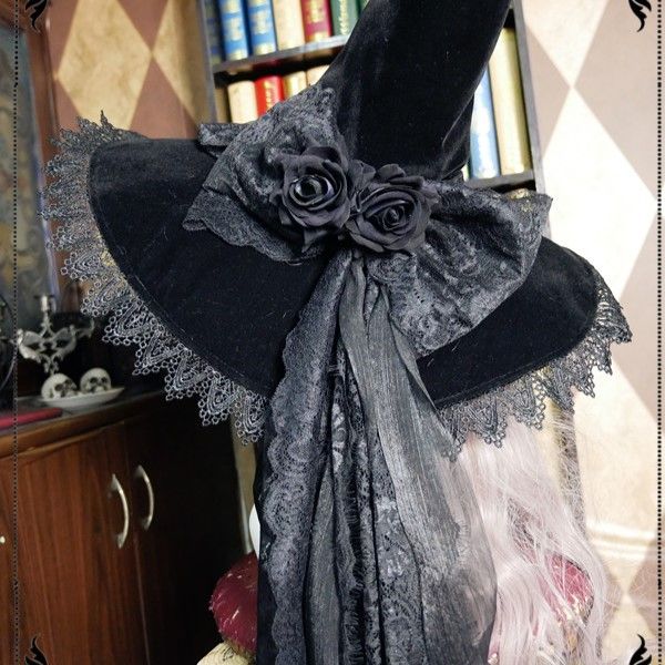 a black hat with lace and flowers on it sitting in front of a book shelf