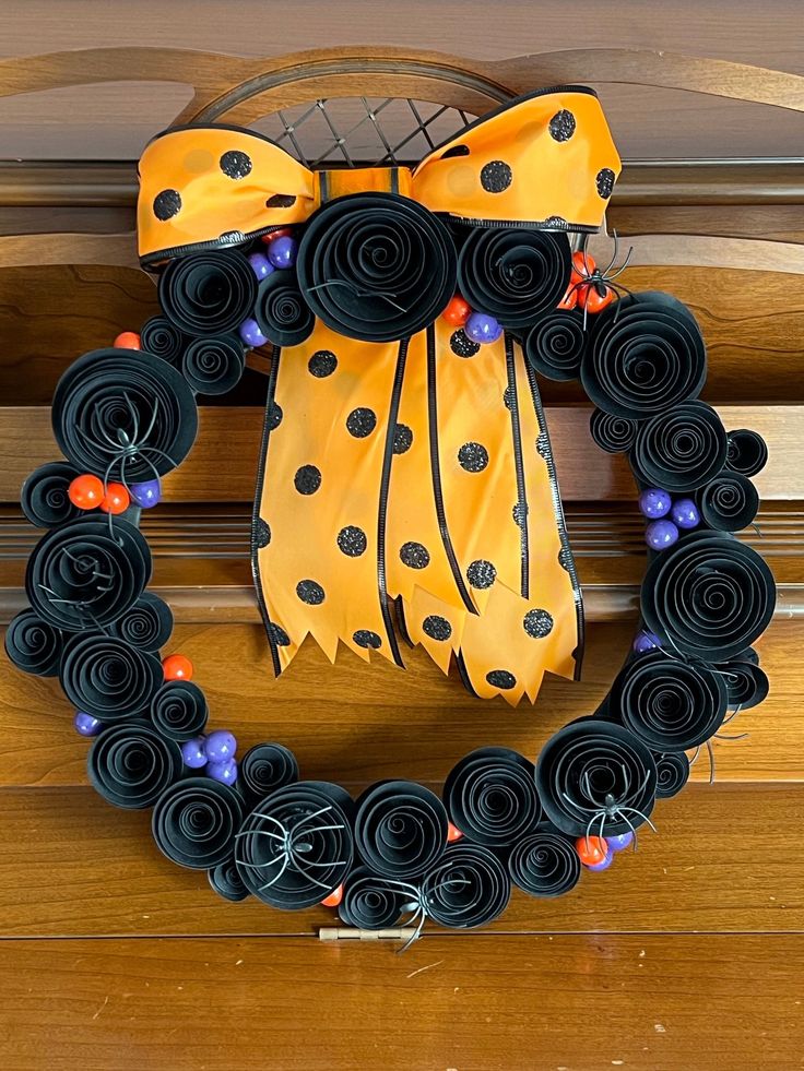 a wreath made out of black paper and yellow ribbon on top of a wooden door