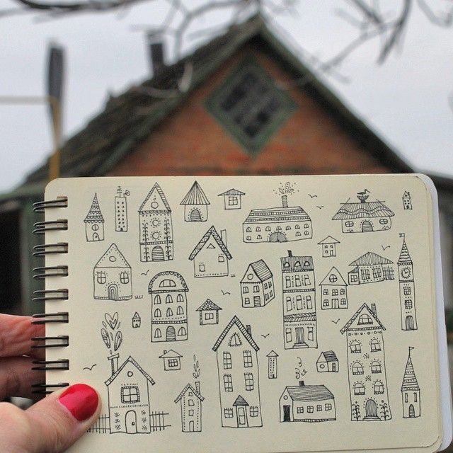 a hand holding a notebook with houses drawn on it