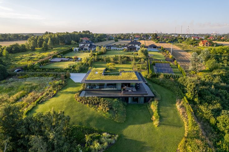 an aerial view of a house surrounded by lush green fields and trees with solar panels on the roof