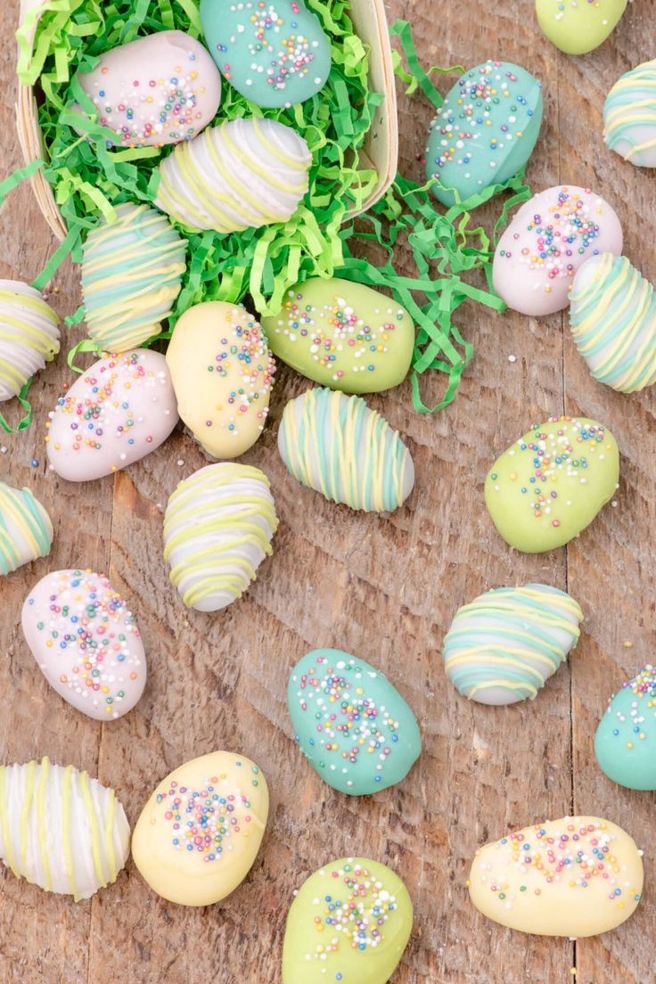 colorfully decorated easter eggs sitting on top of a wooden table next to green grass