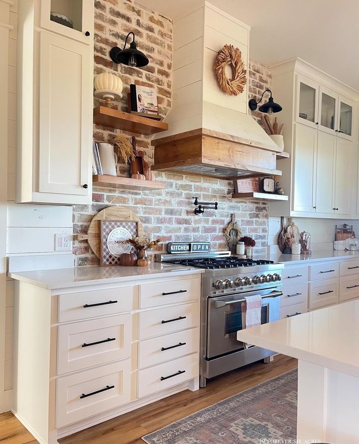 a kitchen with white cabinets and an oven in the center, surrounded by brick walls