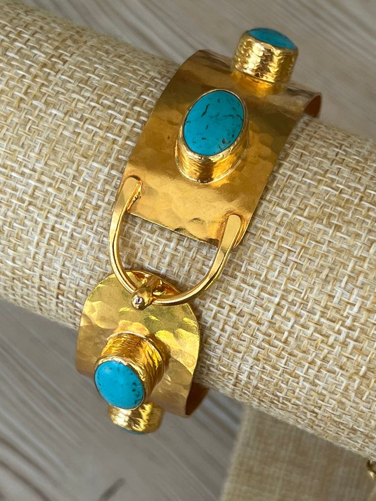 Inspired by ancient artisan jewelry design, the Chakarr Jewelry collection presents the extraordinary Turquoise Byzantine Bracelet, delivering an authentic and unique statement piece. Employing century-old traditions of metal-smithing and casting, this bracelet is meticulously constructed by hand, encasing turquoises, resulting in a truly one-of-a-kind work of art. The brand itself is born from the shared passion of a mother and daughter team, infusing their creations with love, dedication and contemporary elegance with a bohemian vibe. Elegant Turquoise Bracelet With Patina, Elegant Turquoise Bracelets With Patina, Bohemian Bronze Hammered Bracelets, Bohemian Hammered Bronze Bracelets, Artisan Brass Bangle, Artisan Hammered Bracelet Jewelry, Artisan Hammered Bracelet, Artisan Hammered Turquoise Jewelry, Artisan Gold Bracelet With Patina