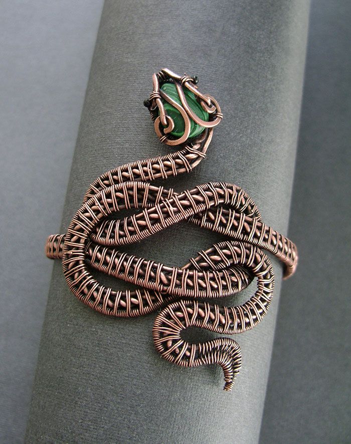 a snake ring is sitting on top of a napkin with a green stone in the middle