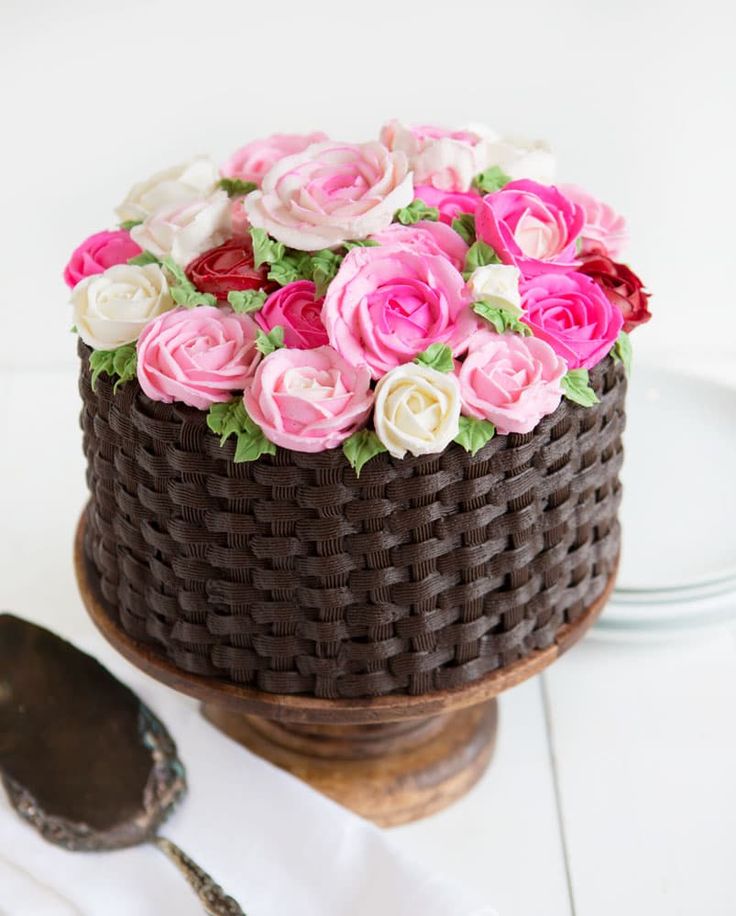 a chocolate cake with pink and white flowers on it sitting on a table next to a plate