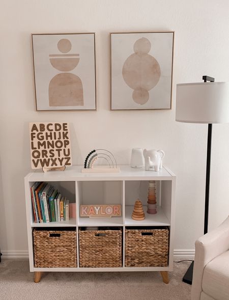 a living room with two pictures on the wall and some baskets in front of it