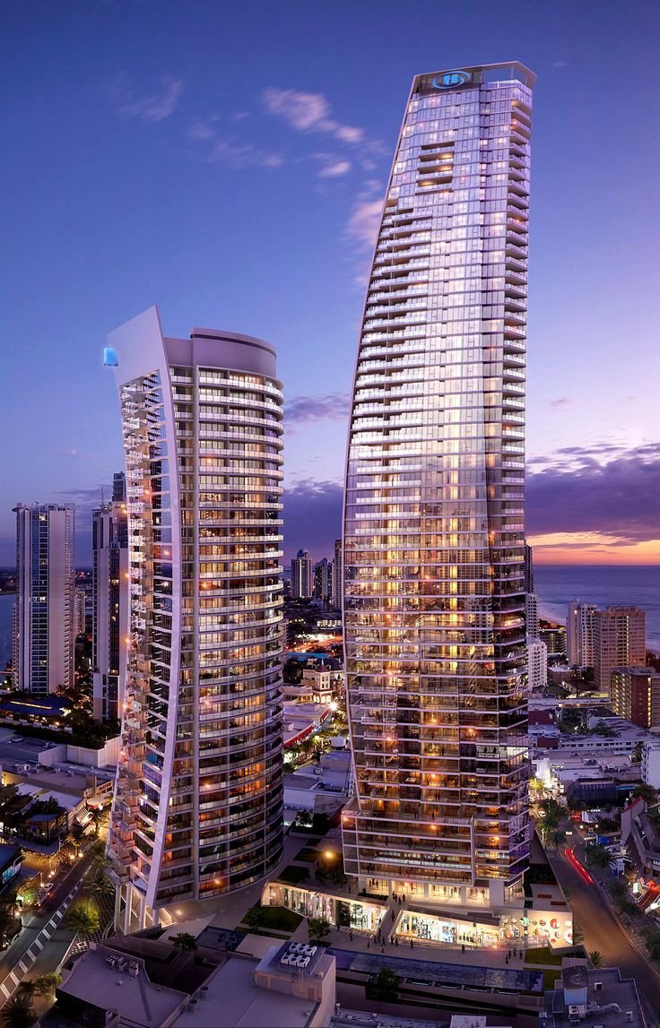 an aerial view of two skyscrapers in the city at night, with lights on