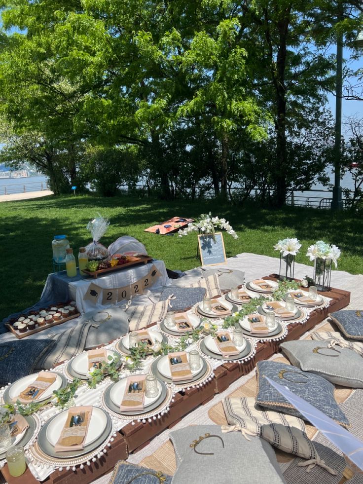 a picnic table with plates and napkins on it in the grass next to trees