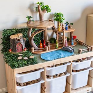 a wooden toy house with lots of toys on it's shelf and storage bins